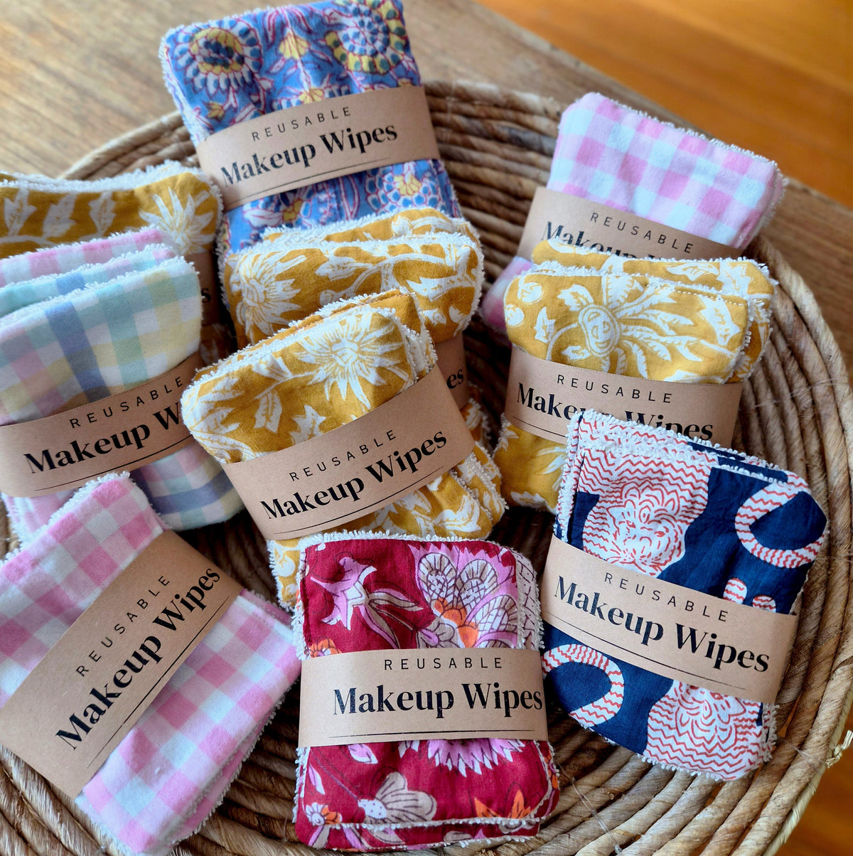  Cosmetic wipesmustard yellow fabric items with a white floral block-print pattern, displayed on a white surface alongside a pink Clarins compact and a black and gold cosmetic tube.