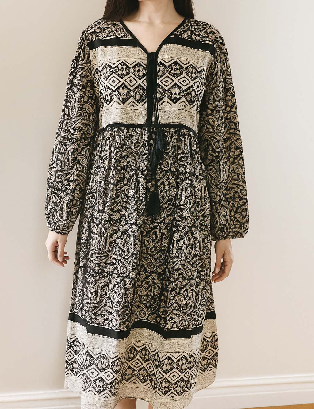 Person wearing a long-sleeve dress with a black and white pattern against a plain background